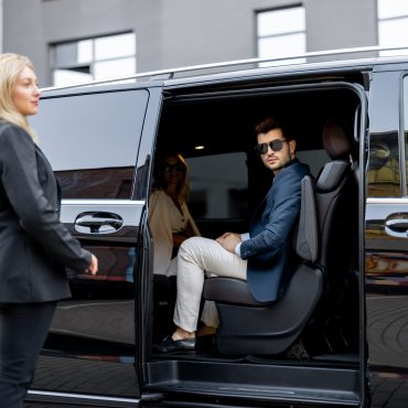 Female chauffeur helps a business people to get out of a vehicle